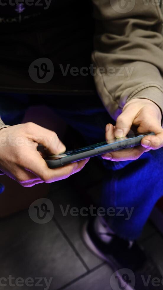 Young man playing mobile game with fast finger movements and colorful pulsating hand lights, dynamic gameplay, close up phone screen, digital entertainment, gaming action, energetic gaming session. photo