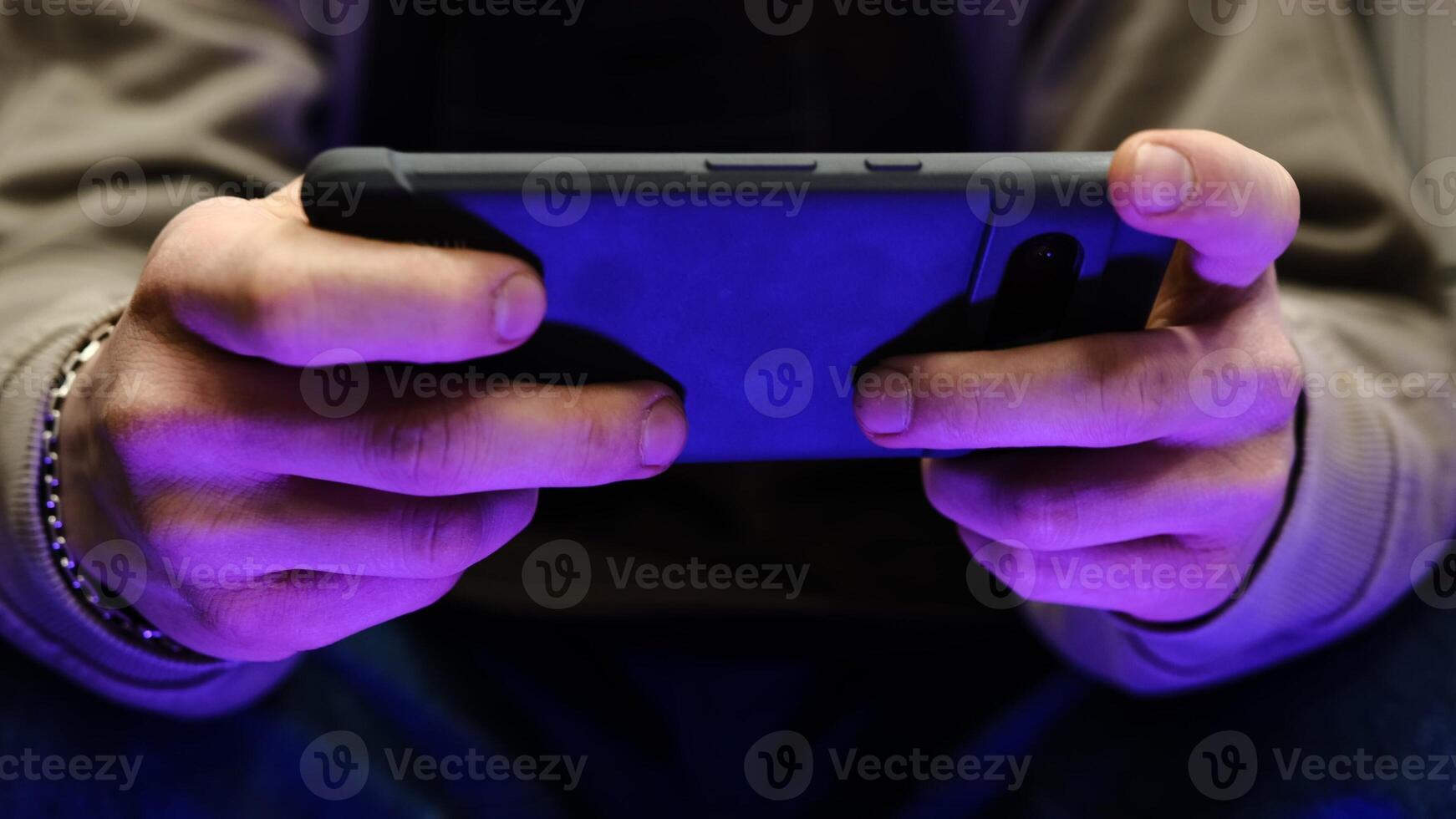Young man playing mobile game with fast finger movements and colorful pulsating hand lights, dynamic gameplay, close up phone screen, digital entertainment, gaming action, energetic gaming session. photo