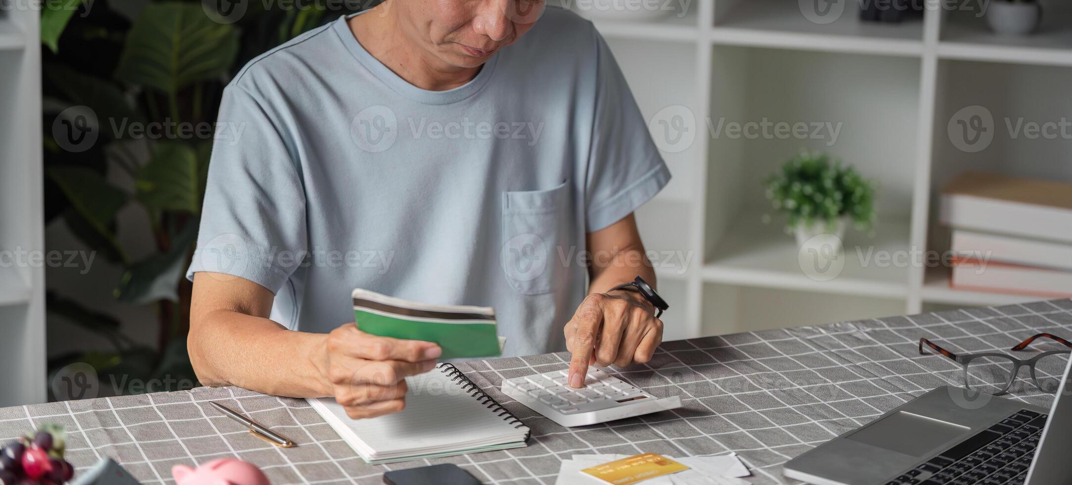 Elderly man calculating savings with a calculator and notebook at home photo