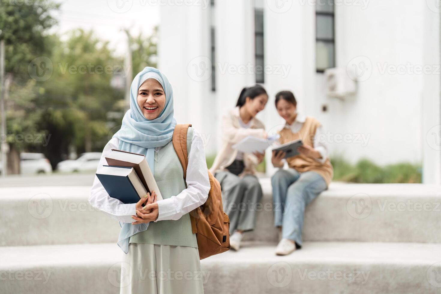 Confident diverse female student holding books with friends studying at university. photo