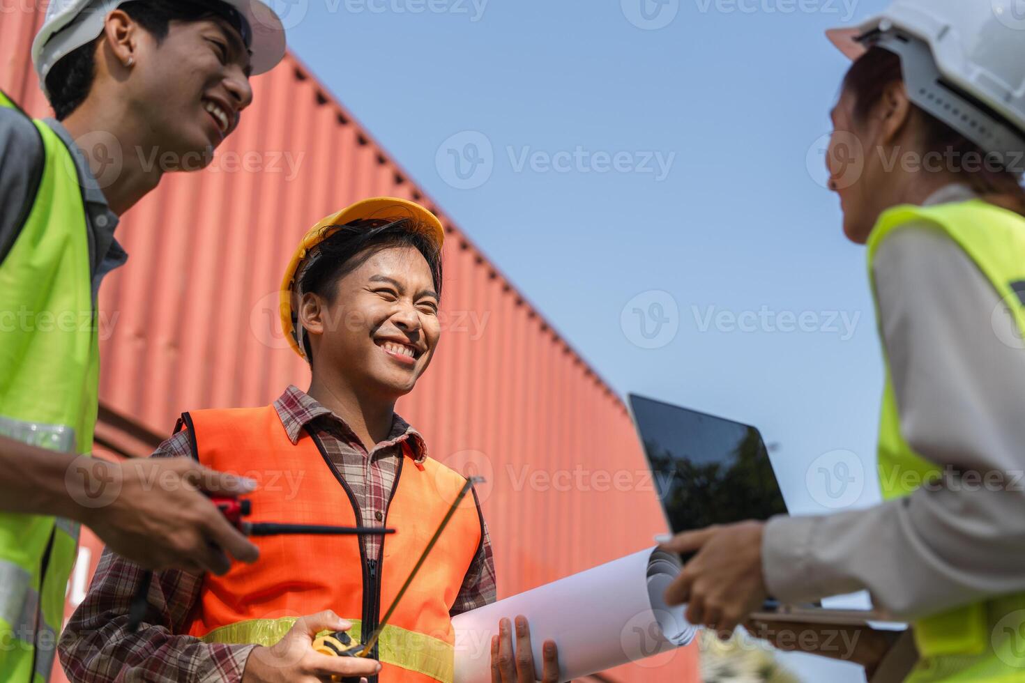 Happy construction team engaging in light hearted discussion engineers collaborating with plans at the site photo
