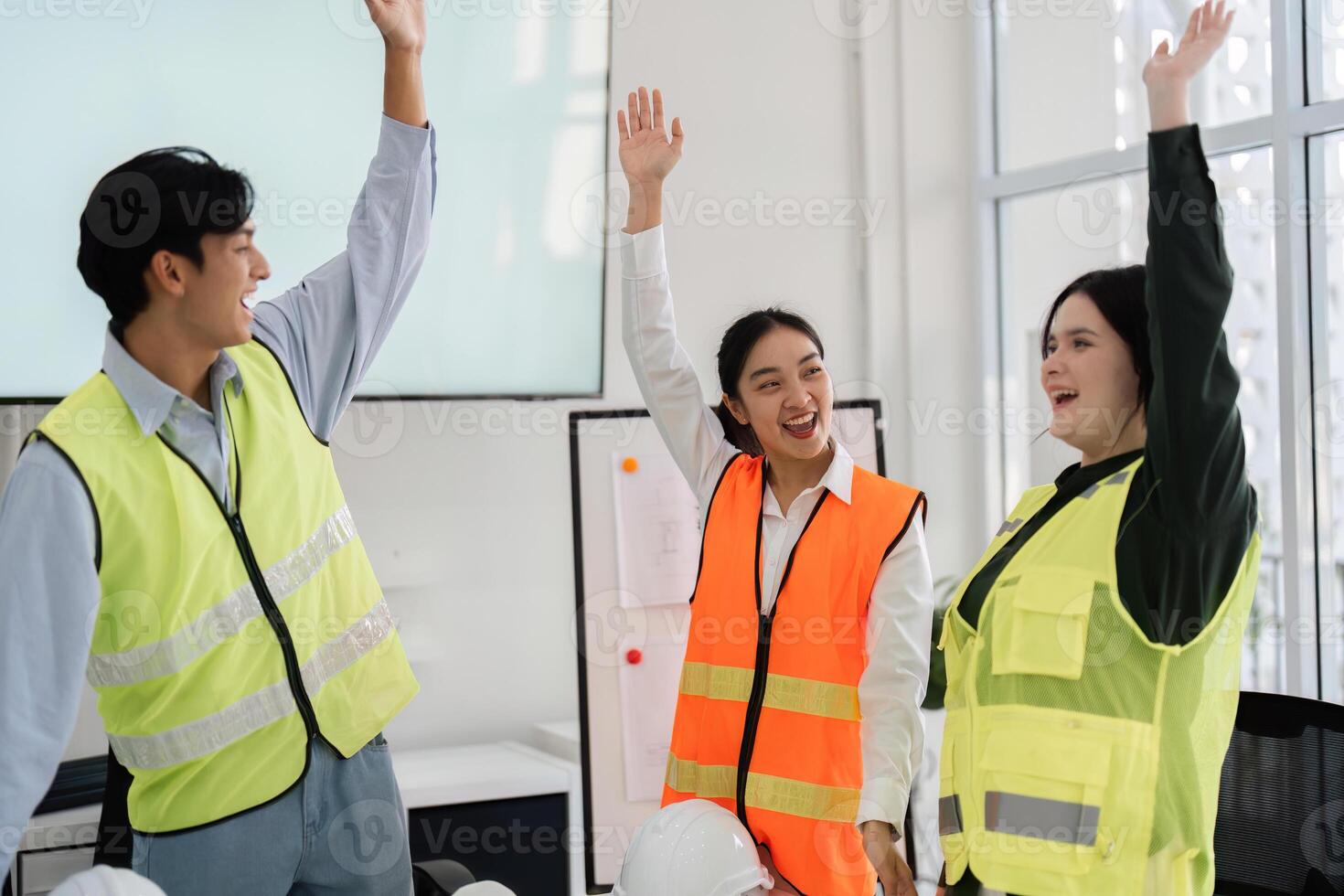 Joyful construction team celebrating success. architect, engineer, and designer raising hands in a modern office photo