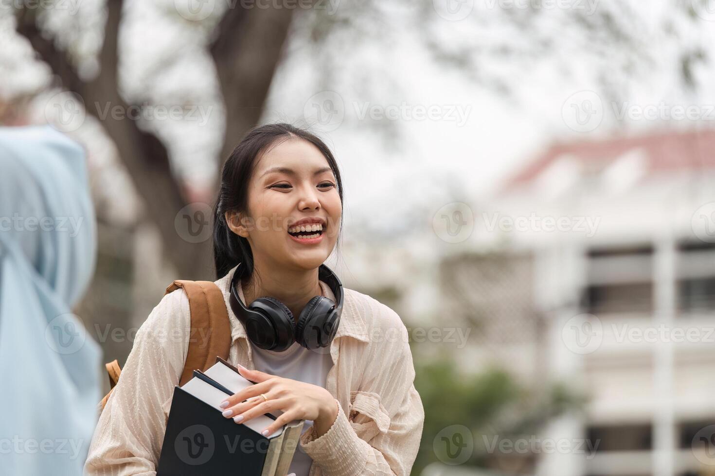 Female student smiling while holding books outdoors on university campus. photo