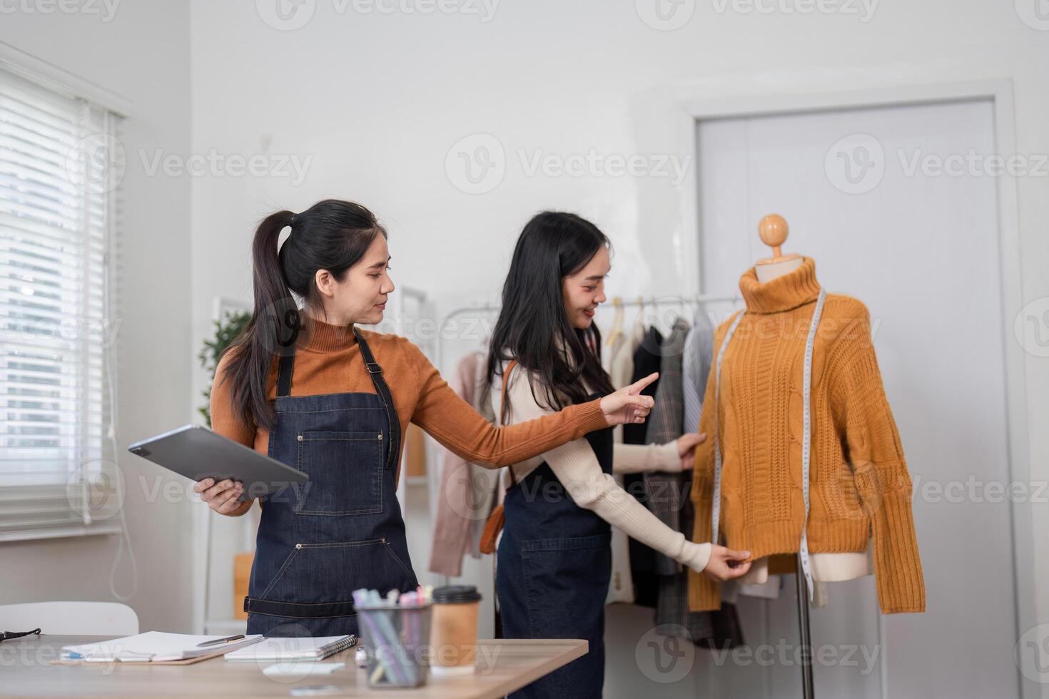 Fashion designers discussing design details while presenting a cozy sweater on a mannequin photo