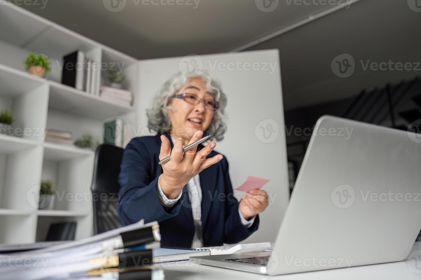 Elderly business woman explaining ideas passionately while conferencing in a modern office photo