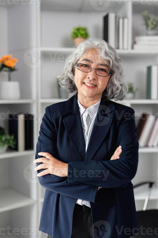 Senior female business executive smiling with arms crossed in a modern office, embodying confidence and expertise photo