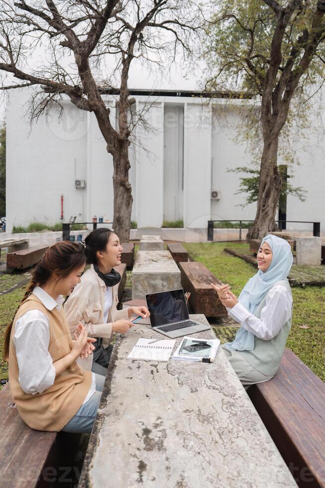 Diverse multicultural women engaged in outdoor study session, sharing ideas and using technology. photo