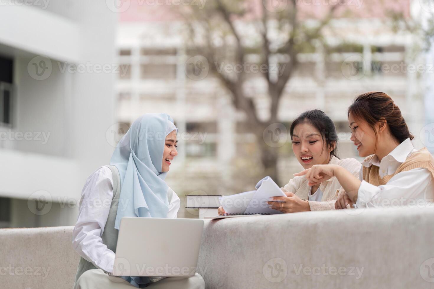 Diverse female students studying together outdoors, sharing notes and ideas. photo