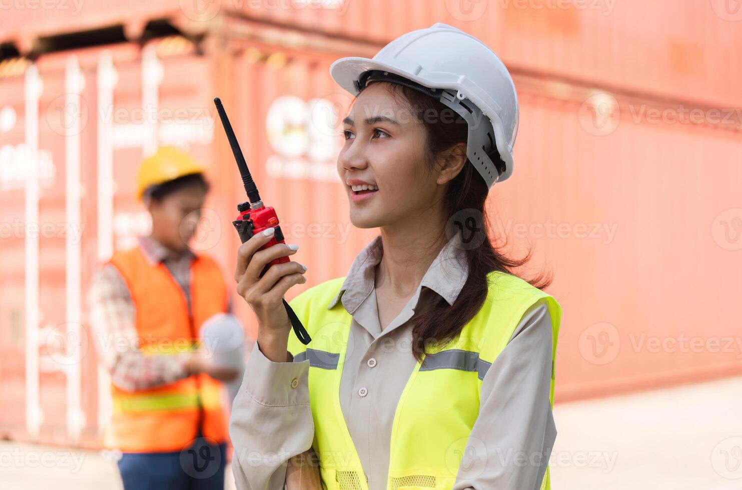 Female construction supervisor communicating effectively on a radio at a shipping container site photo