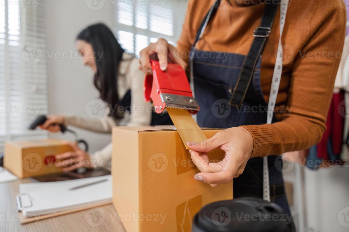 Diverse couple sealing packages for online orders in their boutique workspace. photo