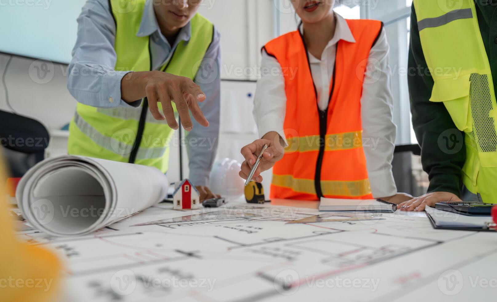 Construction team pointing at project plans and discussing layout details in a professional office setting photo