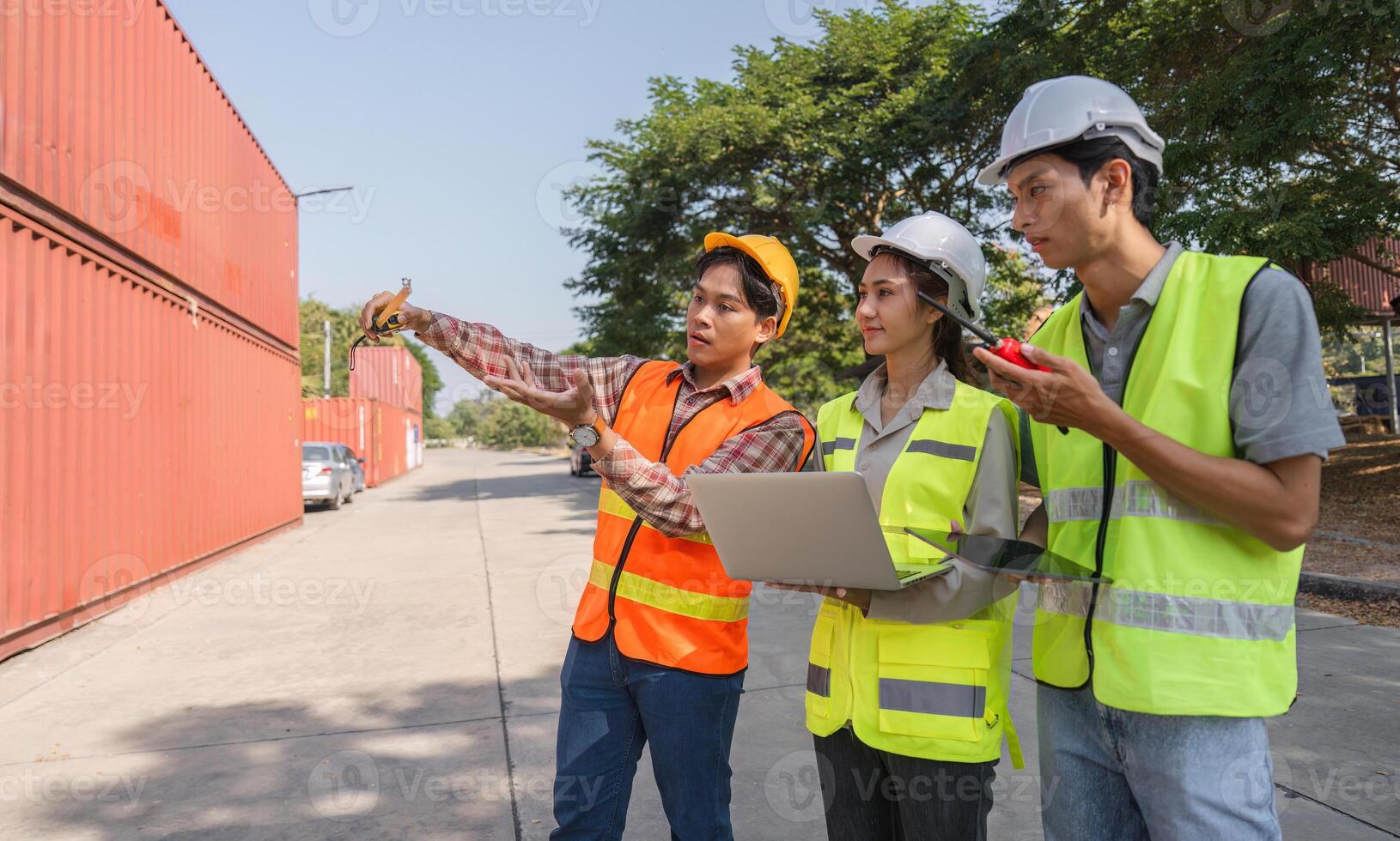 Construction workers strategizing project plans with a laptop and blueprints at a busy construction site photo
