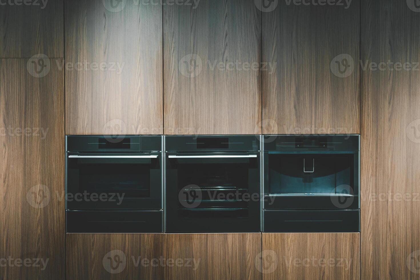 A built-in microwave oven with a digital display, seamlessly integrated into a light wooden kitchen cabinet. Built-in microwave oven close-up in the kitchen photo
