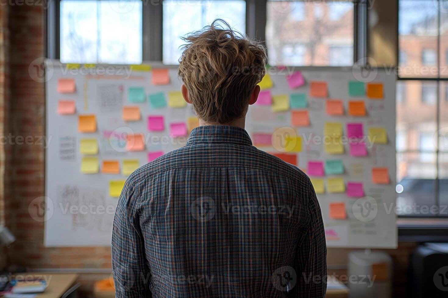 a man look to sticky notes on a task board to organize ideas and workflow in a office.,. photo
