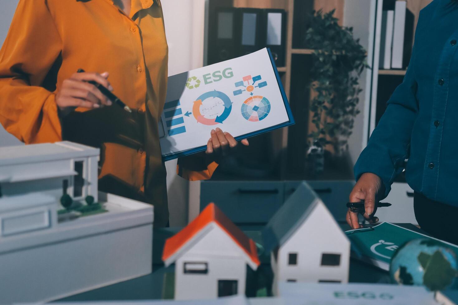 Two people are standing around a table with a house model photo