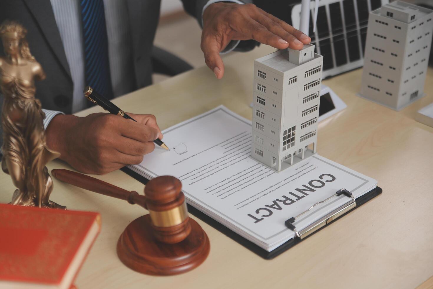 A man signing a contract with a model of a building photo