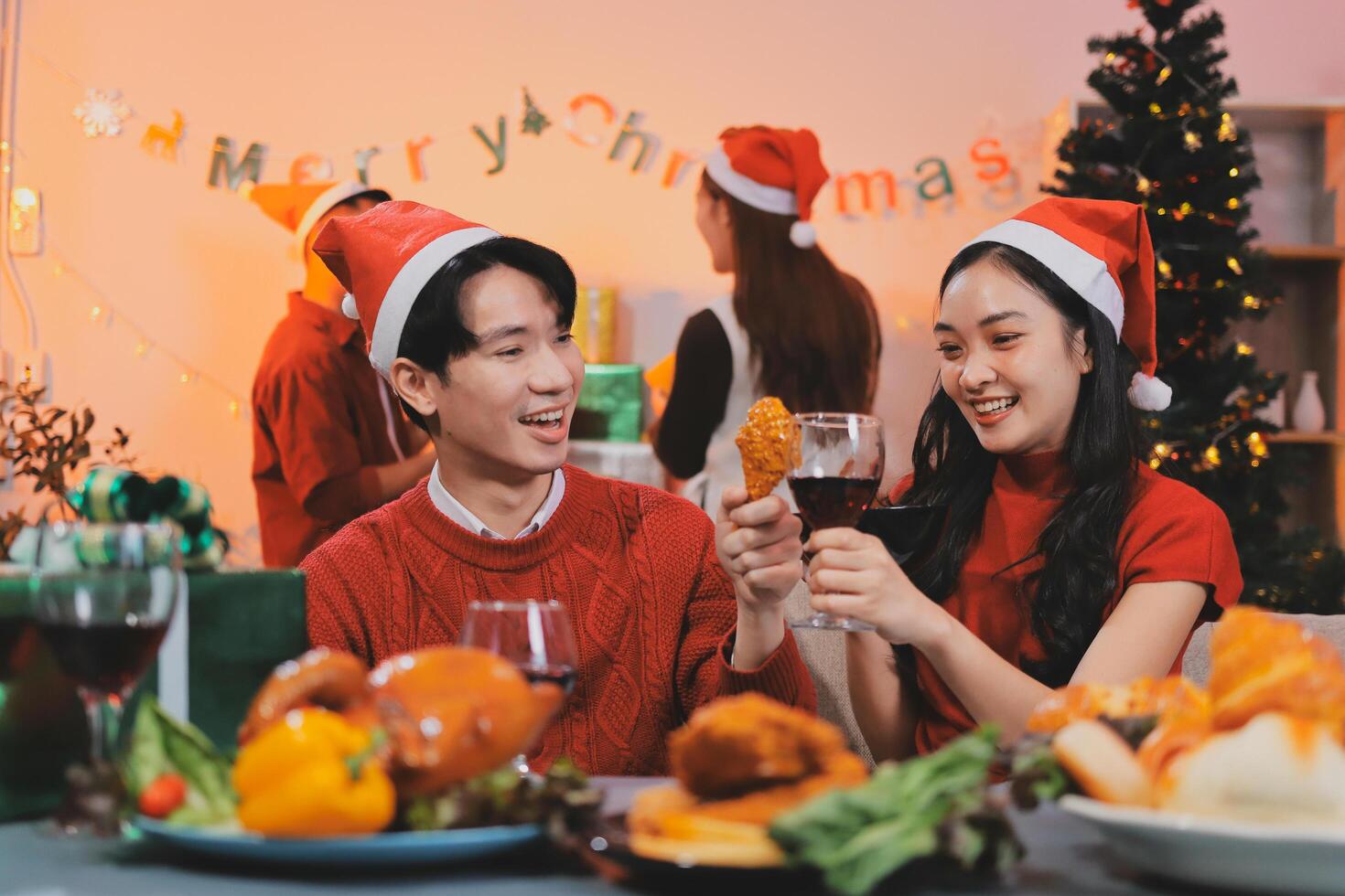 A couple in santa hats and christmas hats are toasting photo