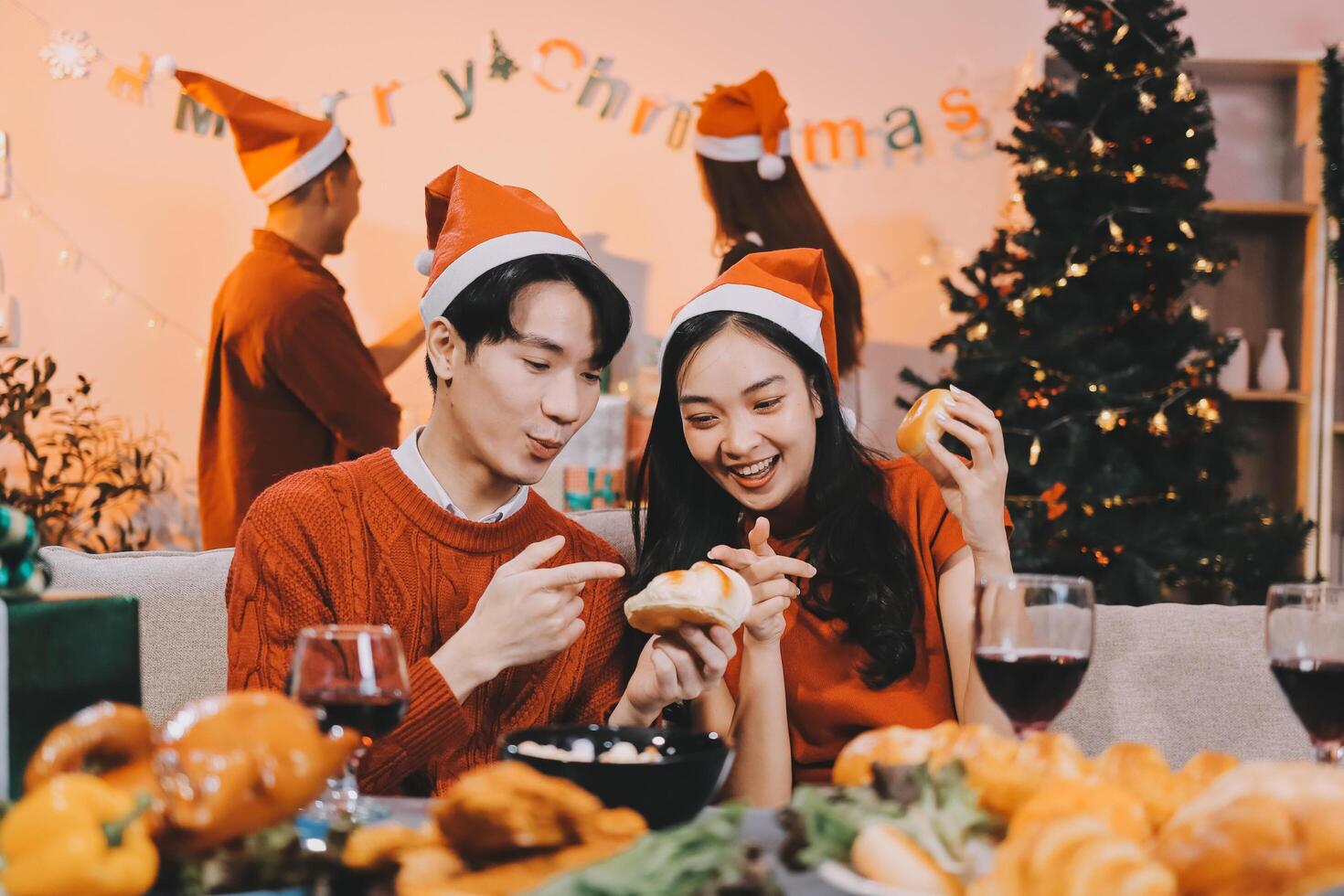 A couple eating christmas food in front of a christmas tree photo