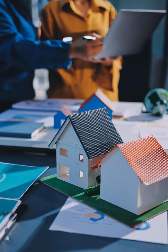 A woman is using a laptop and a house model on a table photo