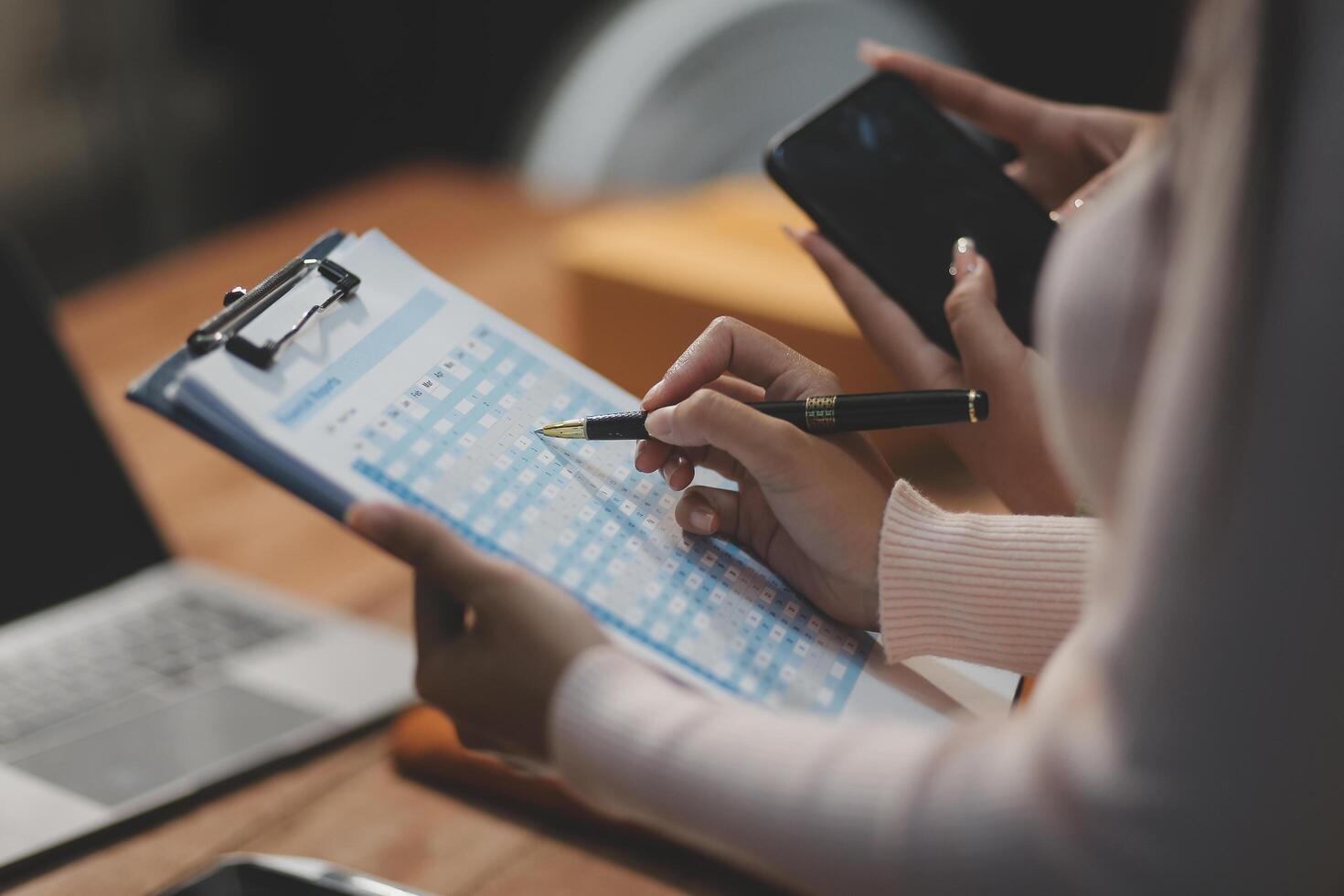 A woman writing on a clipboard with a pen and a smartphone photo