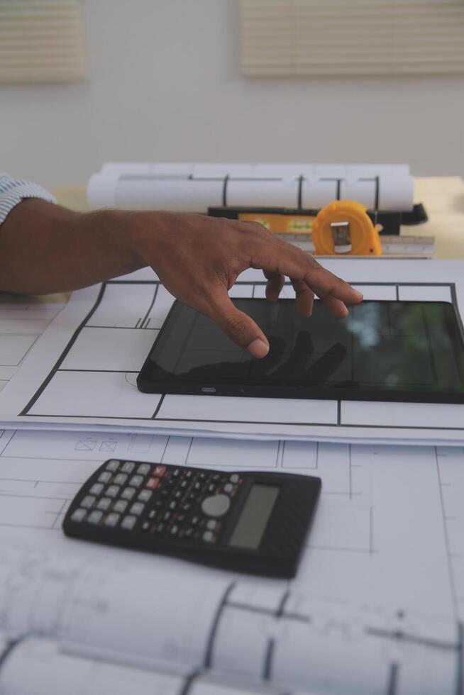 A person using a tablet on a table with construction plans photo