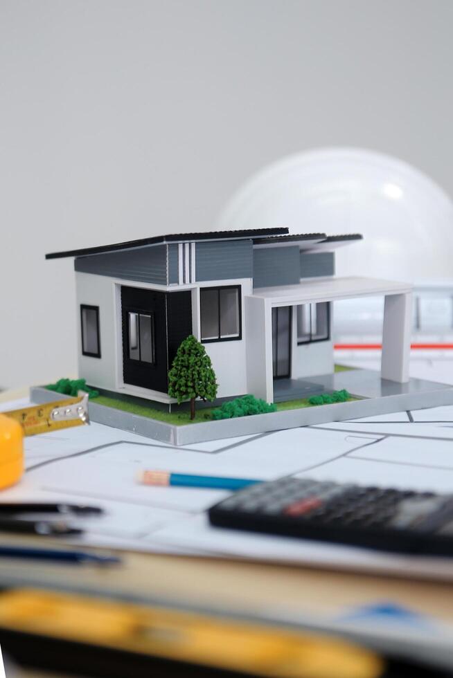A model of a house sits on top of a table with construction tools photo