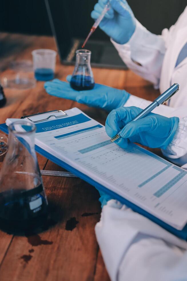 Two people in lab coats and gloves are working on a clipboard photo