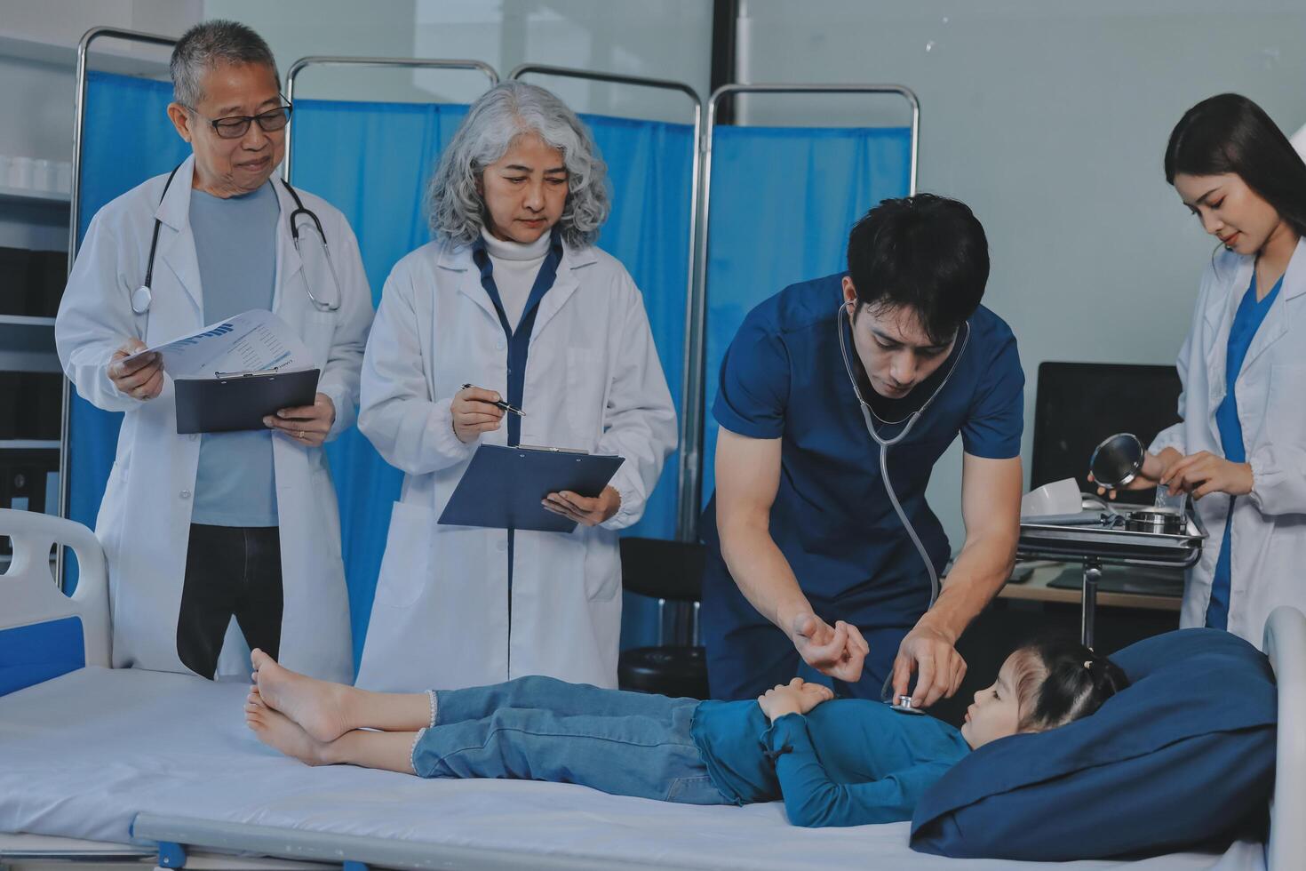 A group of doctors and nurses standing around a child in a hospital bed photo