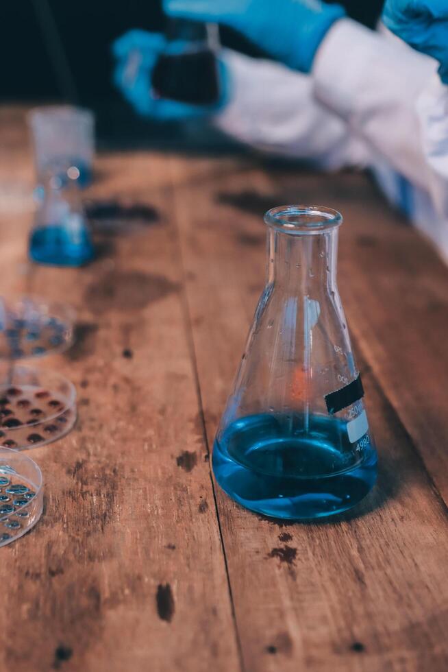 A person in a lab coat is holding a beaker photo
