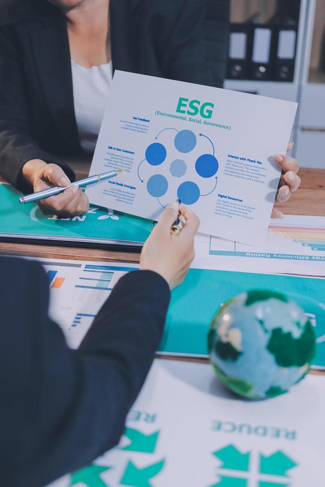 Business people sitting at a table with a paper with the esg logo photo
