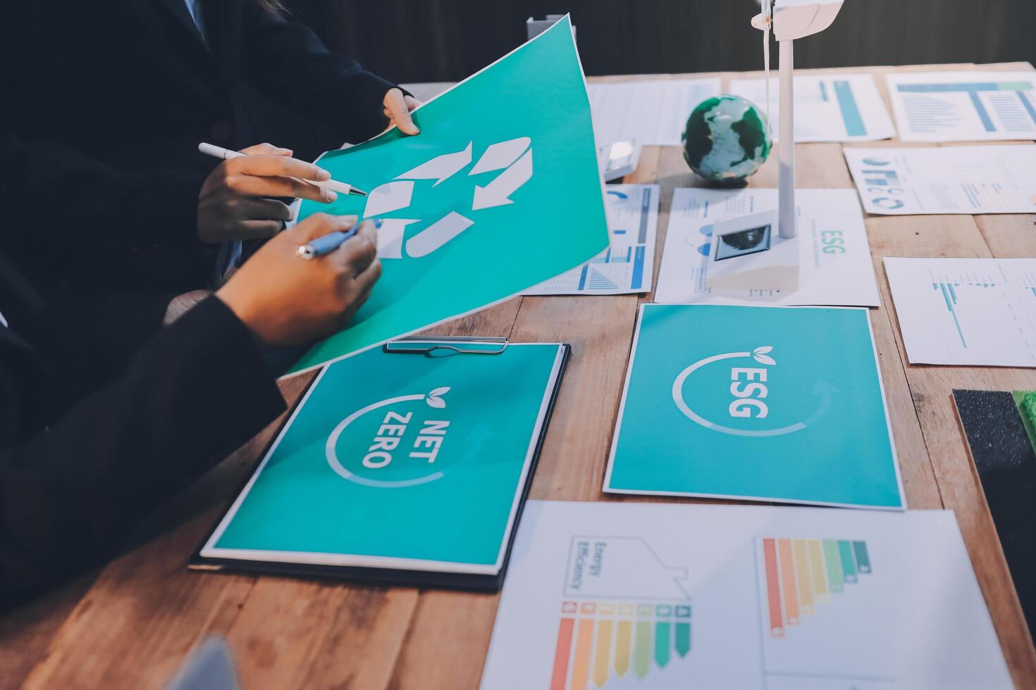 Business people working on a table with papers and green recycling signs photo