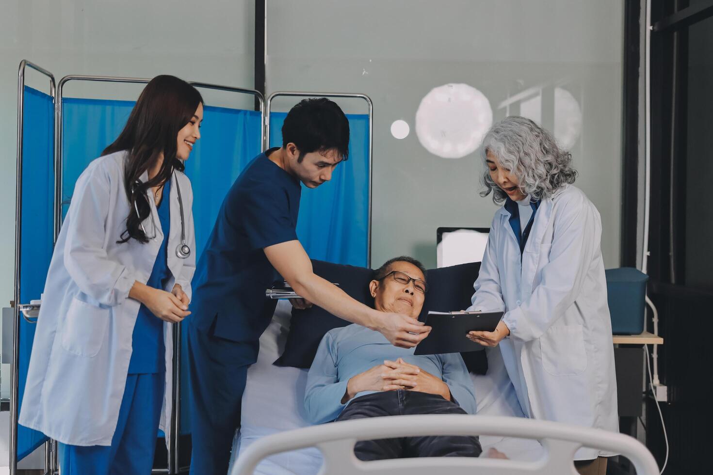A group of doctors and nurses standing around a patient in a hospital bed photo