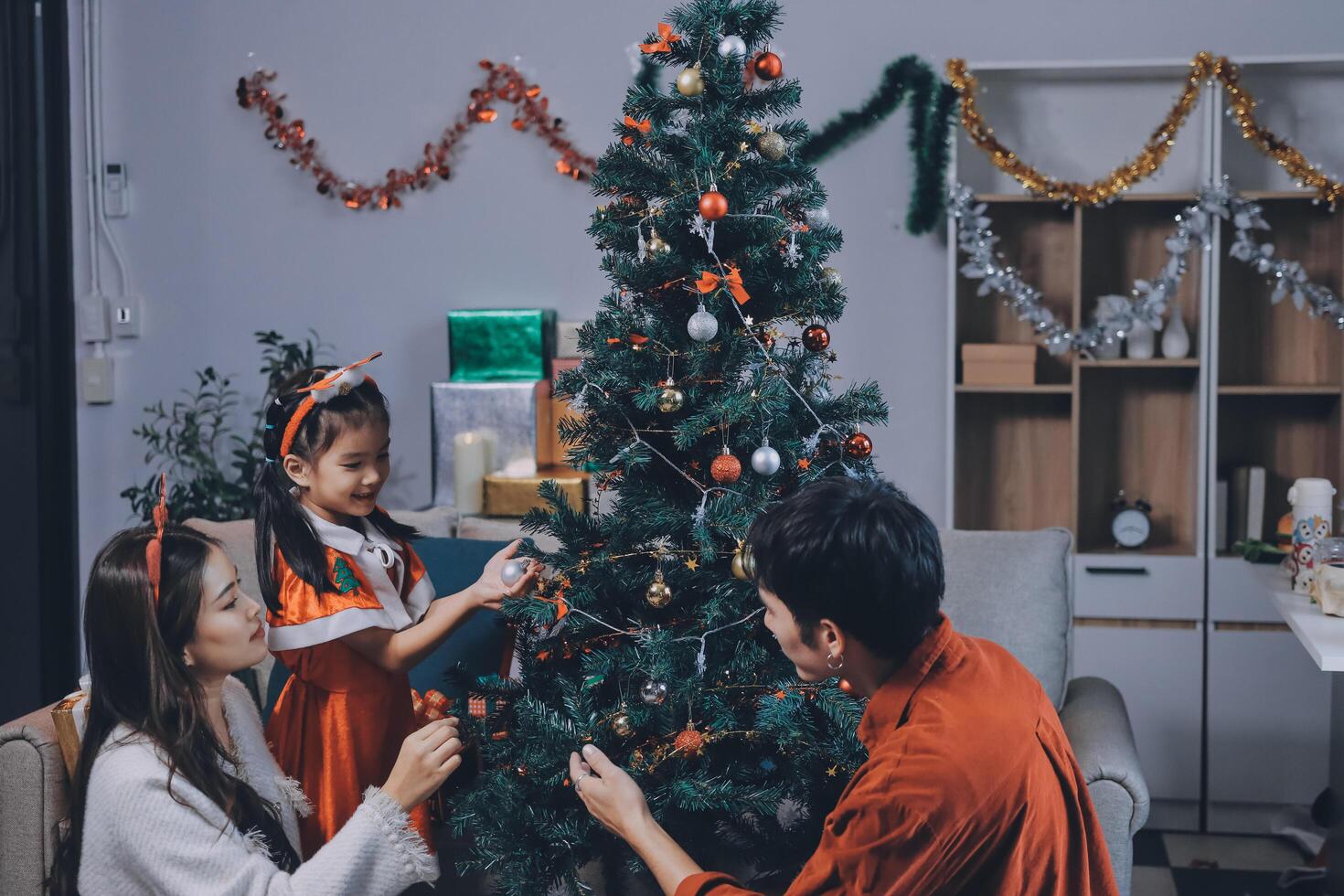 Asian family decorating christmas tree in living room photo