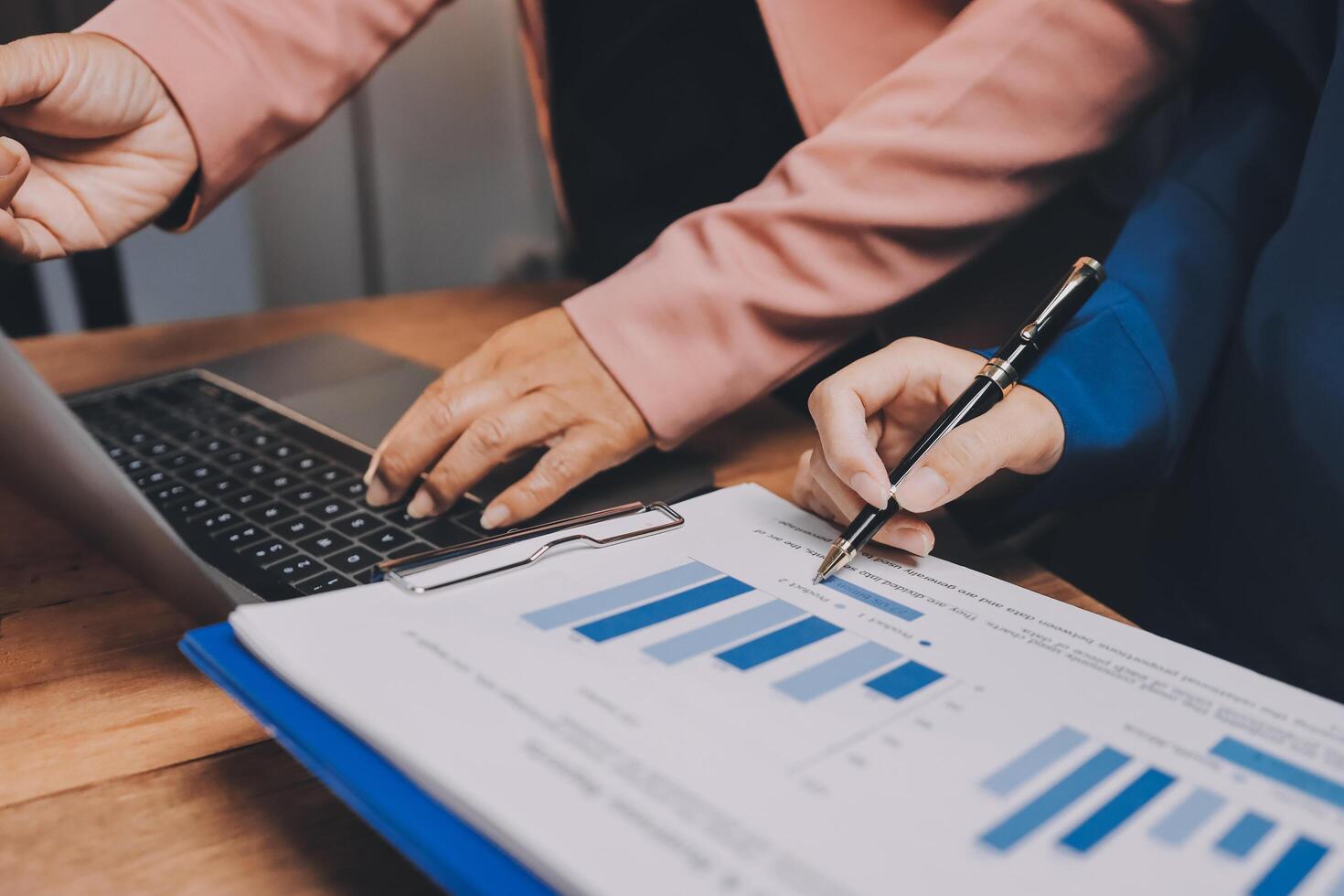 Two people working on a laptop and a paper with graphs photo