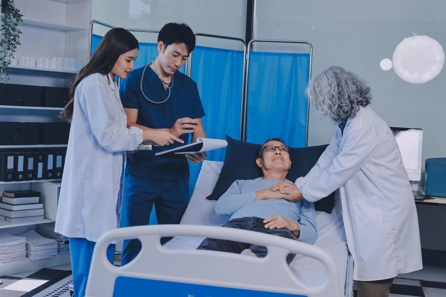A group of doctors and nurses standing around a patient in a hospital bed photo