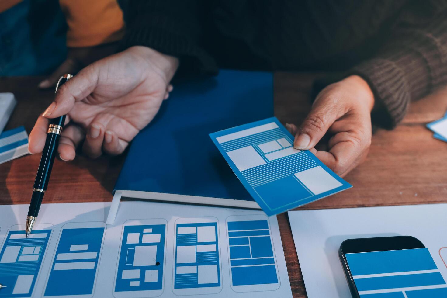 A person is holding a smartphone and a notebook with a blue paper photo