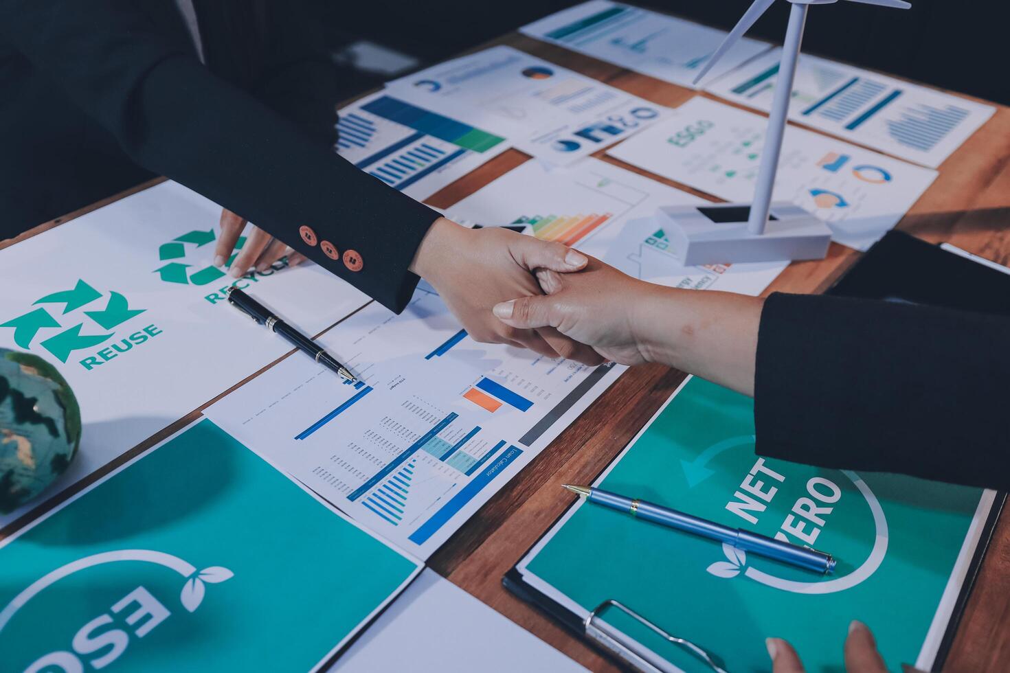 Business people shaking hands over papers with eco-friendly logo photo