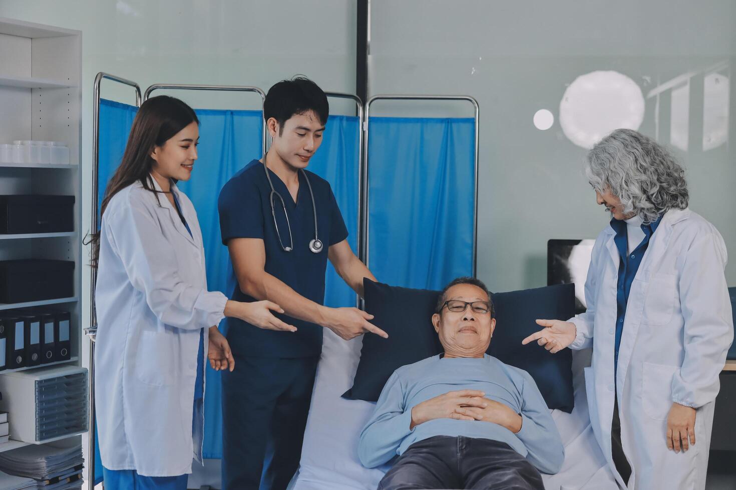 A group of doctors and nurses standing around a patient in a hospital bed photo