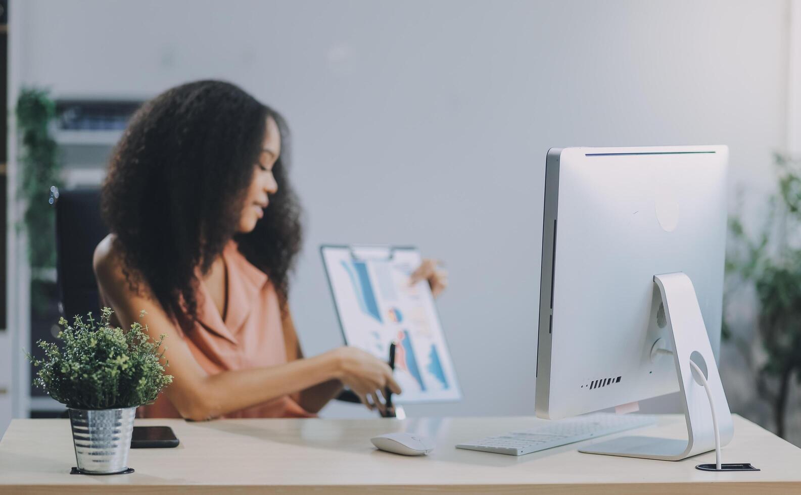 A woman sitting at a desk with a computer and a plant photo