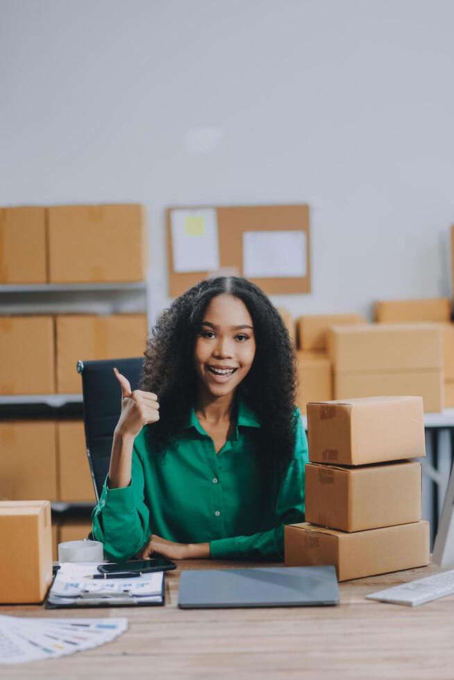 A woman sitting at a desk with boxes and a laptop photo