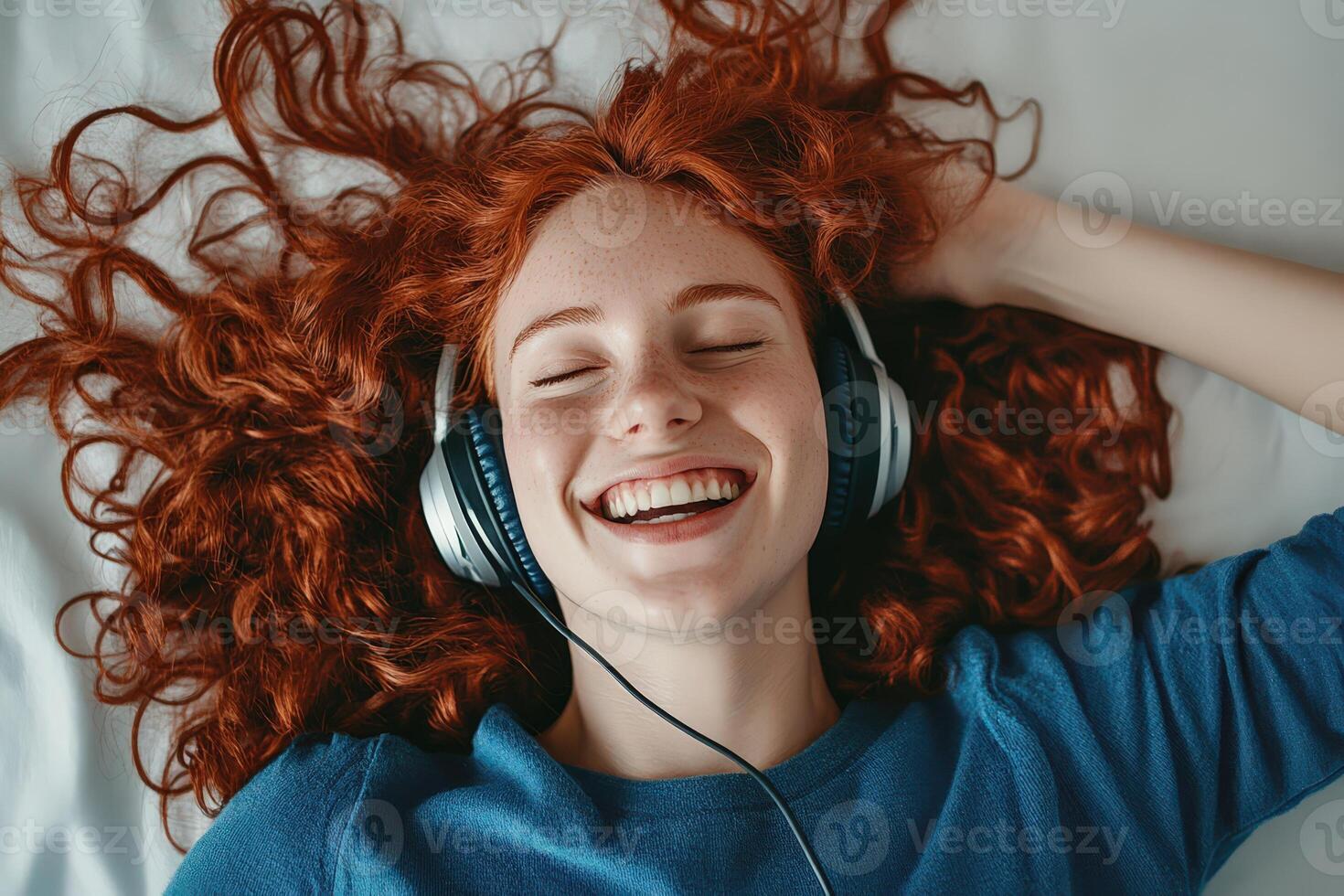 Happy woman enjoying music with headphones, showcasing her vibrant red hair photo