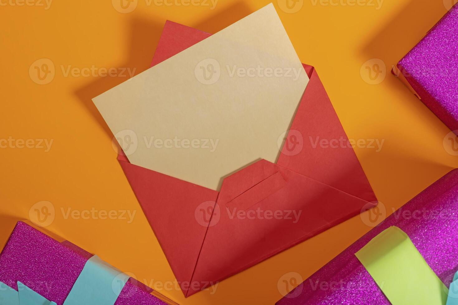 Red envelope containing a letter placed on an orange background surrounded by gift boxes. photo