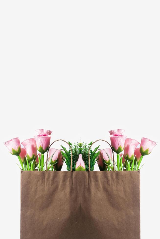 Fresh pink flowers in a brown paper bag with a white background photo