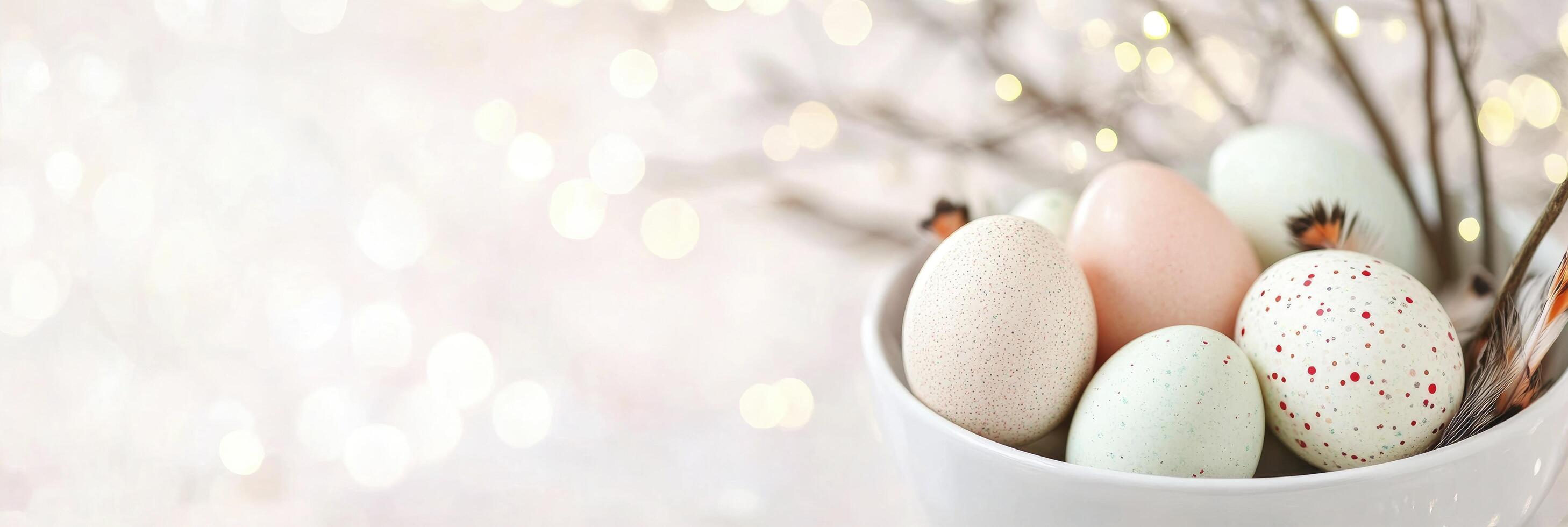 light pink easter eggs in a white bowl and willow branches on a background photo