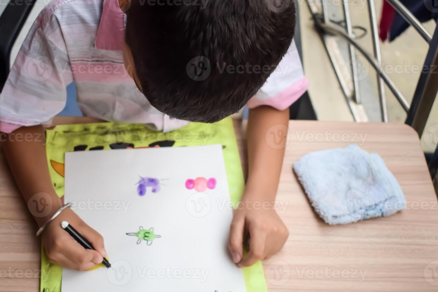 A young boy is drawing on a piece of paper photo