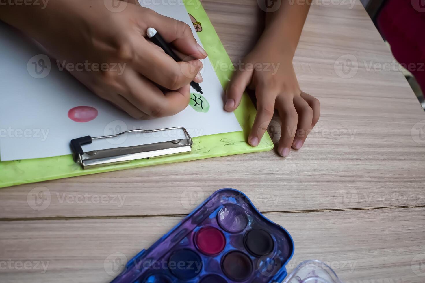 A child's hands are holding a pen and a paintbrush photo