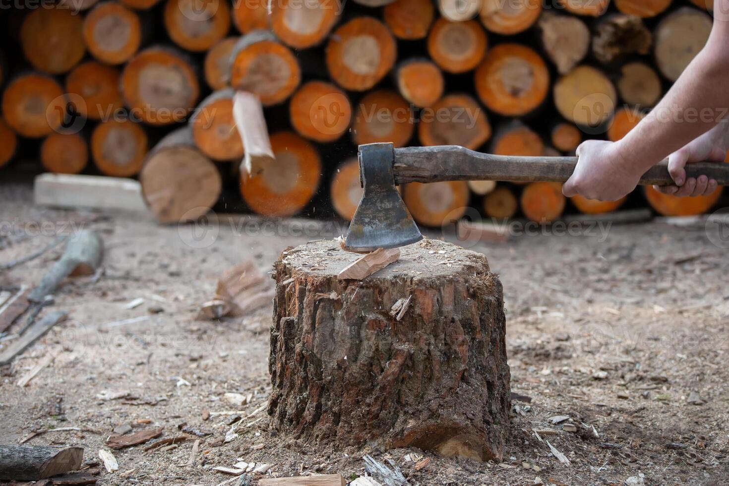 The hand of a woodcutter chops wood with a sharp axe, chips fly around. photo
