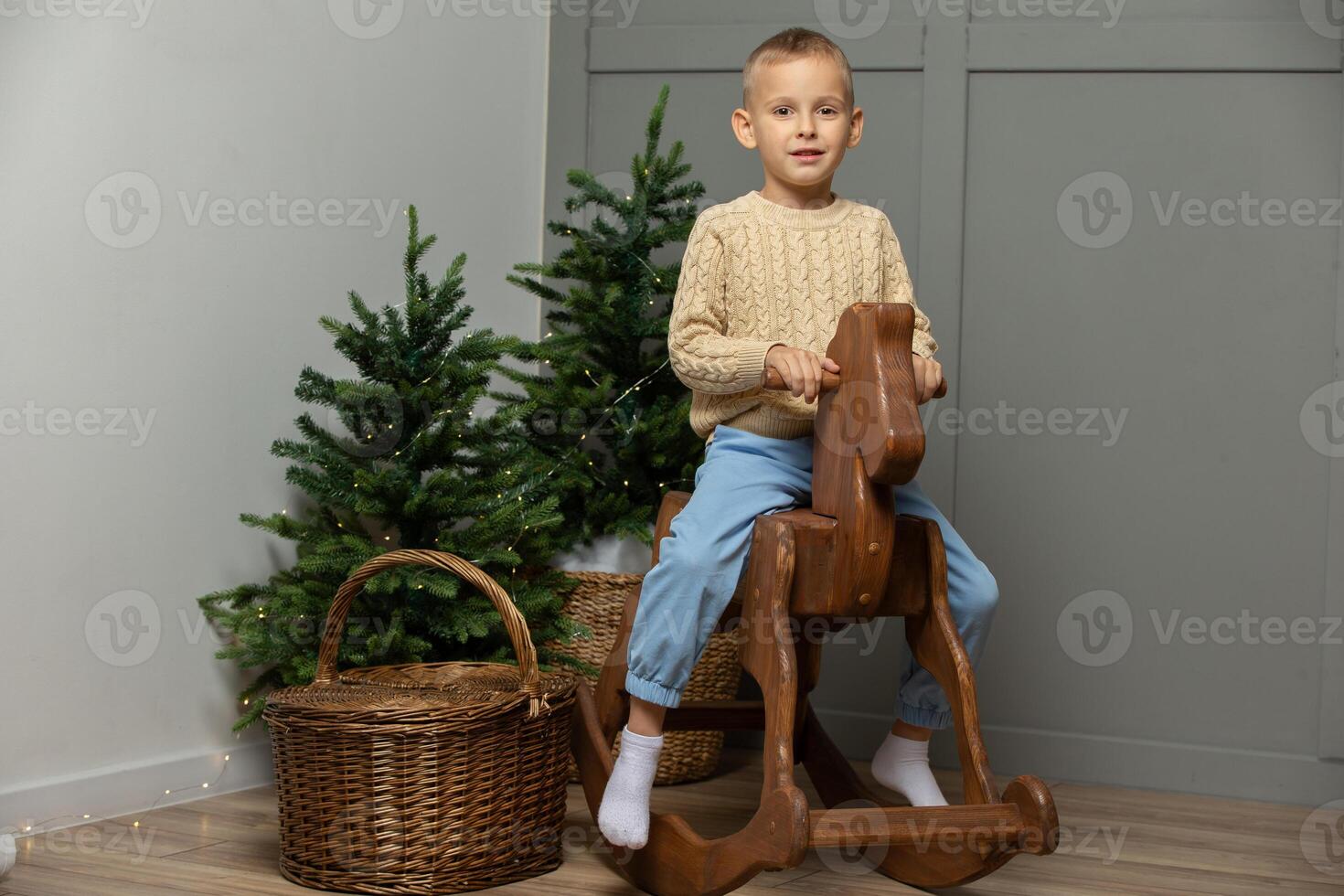 Happy little boy rides on a wooden horse gurney in the Christmas room. photo
