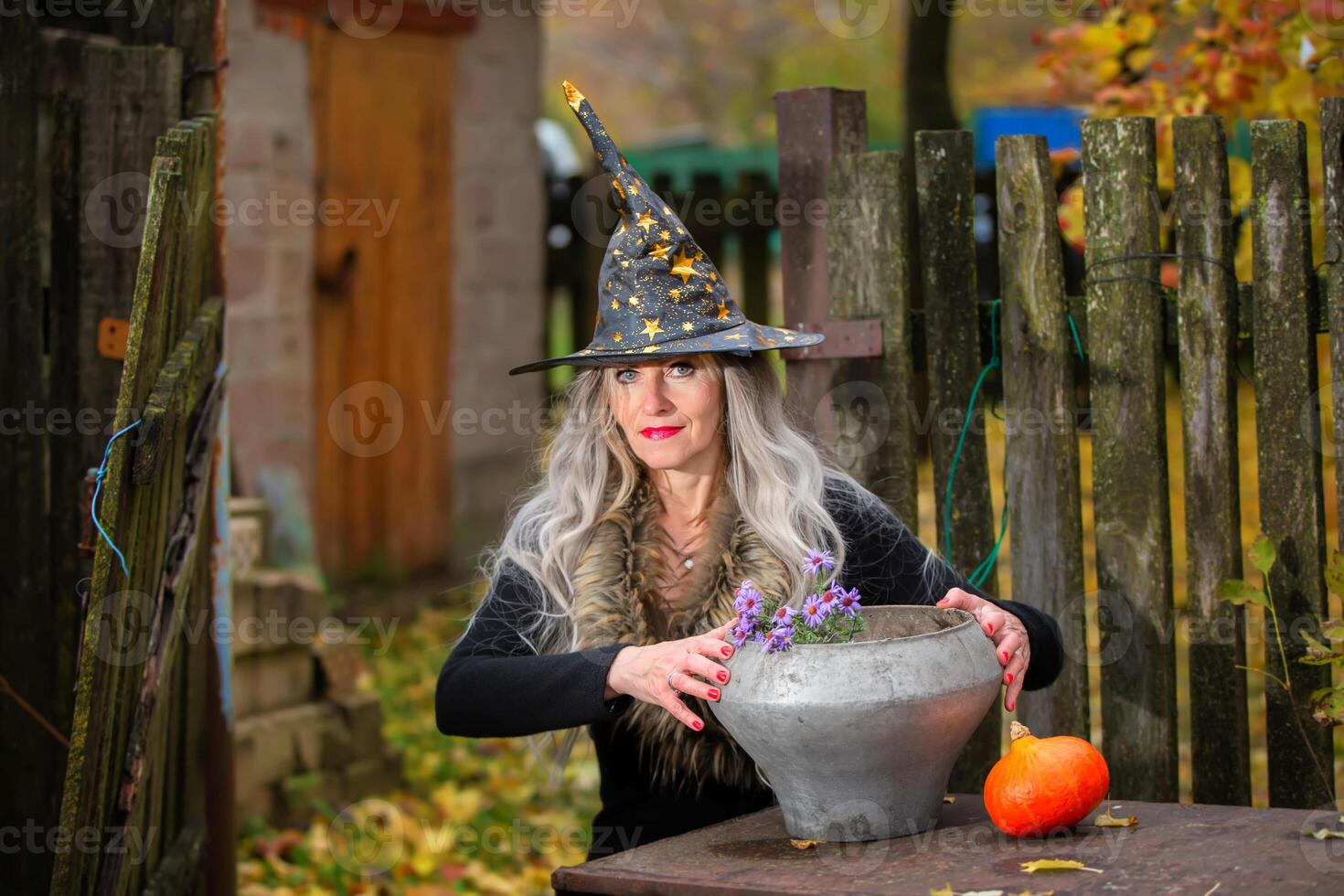 Halloween girl with a magic bowler hat in a witch hat performs witchcraft against an old creepy background. photo