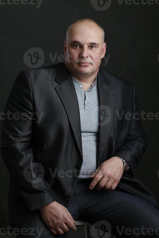 The portrait of a respectable middle-aged businessman in a classic suit on a gray background. photo